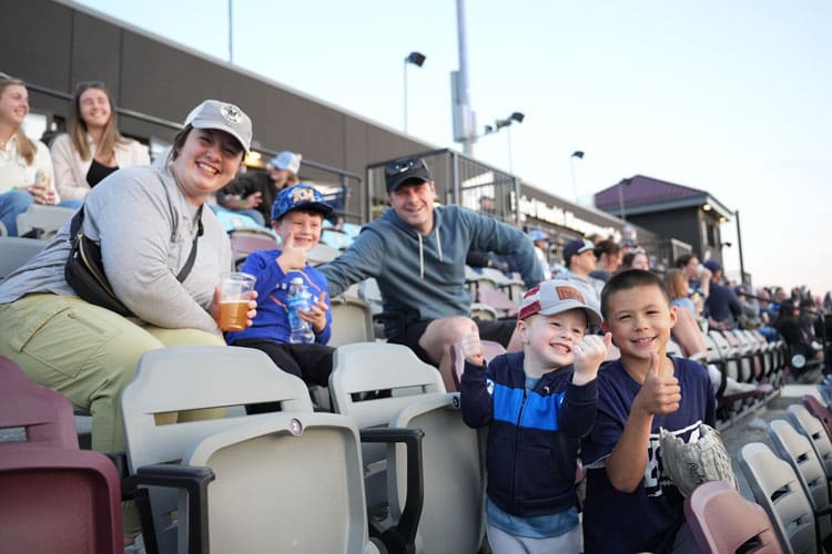 Family and friends sitting together in the dugout seats at WBC Park